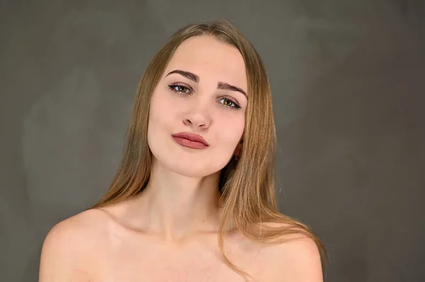 Horisontell skönhet foto av en vacker flicka med långt hår och bra makeup och bra hud. Universal koncept kvinnligt porträtt på en grå bakgrund. — Stockfoto