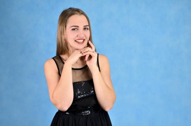 Mavi arka planda bir kadının evrensel konsept yatay portresi. Siyah elbiseli, uzun saçlı ve mükemmel makyajlı güzel bir kızın fotoğrafı farklı pozlarda duruyor..