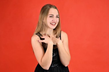 Kırmızı arka planda evrensel konsept yatay kadın portresi. Siyah elbiseli, uzun saçlı ve mükemmel makyajlı güzel bir kızın fotoğrafı farklı pozlarda duruyor..