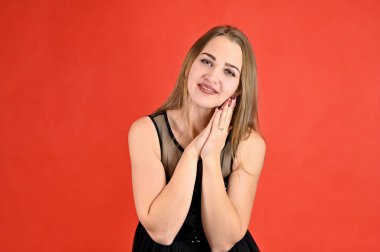 Kırmızı arka planda evrensel konsept yatay kadın portresi. Siyah elbiseli, uzun saçlı ve mükemmel makyajlı güzel bir kızın fotoğrafı farklı pozlarda duruyor..