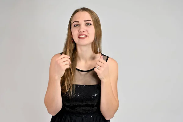 Universal concept horizontal portrait of a woman on a white background. A photo of a pretty smiling girl with long hair and excellent make-up in a black dress stands in different poses. — Stock Photo, Image