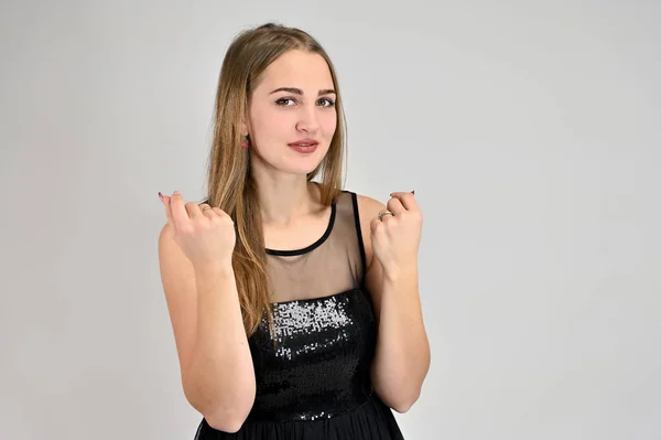 Concepto universal retrato horizontal de una mujer sobre un fondo blanco. Una foto de una chica muy sonriente con el pelo largo y excelente maquillaje en un vestido negro se para en diferentes poses . — Foto de Stock