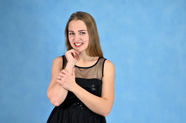 Universal concept horizontal portrait of a woman on a blue background. A photo of a pretty smiling girl with long hair and excellent make-up in a black dress stands in different poses. — Stock Photo, Image