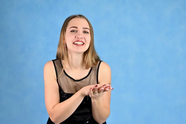 Universal concept horizontal portrait of a woman on a blue background. A photo of a pretty smiling girl with long hair and excellent make-up in a black dress stands in different poses. — Stock Photo, Image