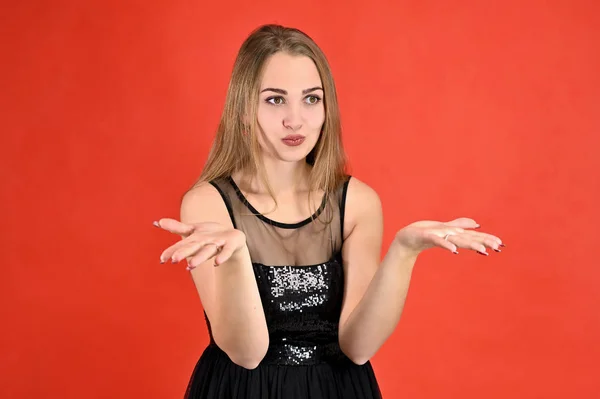 Universal concept horizontal female portrait on a red background. A photo of a pretty smiling girl with long hair and excellent make-up in a black dress stands in different poses. — 스톡 사진