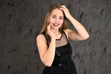 Gri arka planda evrensel yatay kadın portresi konsepti. Siyah elbiseli, uzun saçlı ve mükemmel makyajlı güzel bir kızın fotoğrafı farklı pozlarda duruyor..