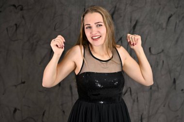 Siyah elbiseli, uzun saçlı ve mükemmel makyajlı güzel bir kızın fotoğrafı farklı pozlarda duruyor. Gri arka planda yatay kadın portresi evrensel kavramı.