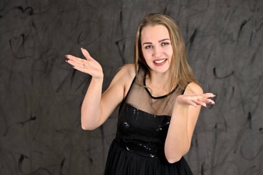 Siyah elbiseli, uzun saçlı ve mükemmel makyajlı güzel bir kızın fotoğrafı farklı pozlarda duruyor. Gri arka planda yatay kadın portresi evrensel kavramı.