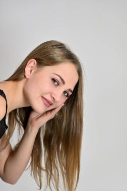 Beyaz arka planda kozmetik reklamcılığı için genel kadın portresi konsepti. Uzun saçlı ve mükemmel makyajlı güzel bir kızın büyük bir fotoğrafı farklı pozlarda duruyor..