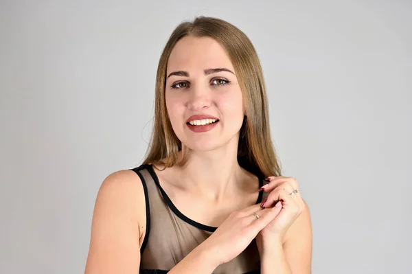 Ett stort foto av en ganska leende flicka med långt hår och utmärkt make-up står i olika poser. Generiska kvinnliga porträtt koncept för kosmetika reklam på en vit bakgrund. — Stockfoto