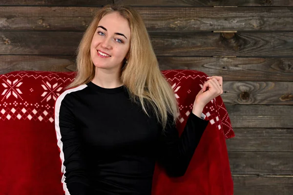 Портрет красивой молодой блондинки с минимальным макияжем в спортивном платье на деревянном фоне. Сидит на красном диване напротив камеры в различных позах . — стоковое фото