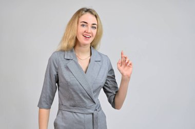 Çeşitli pozlarda kameranın önünde duran bir model. Beyaz bir arka planda gri bir takım elbise içinde asgari makyajlı sevimli, gülümseyen sarışın bir iş kadını portresi..