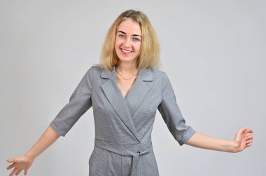 Beyaz bir arka planda gri bir takım elbise içinde asgari makyajla gülümseyen sevimli sarışın bir iş kadınının portresi. Çeşitli pozlarda kameranın önünde duran bir model..