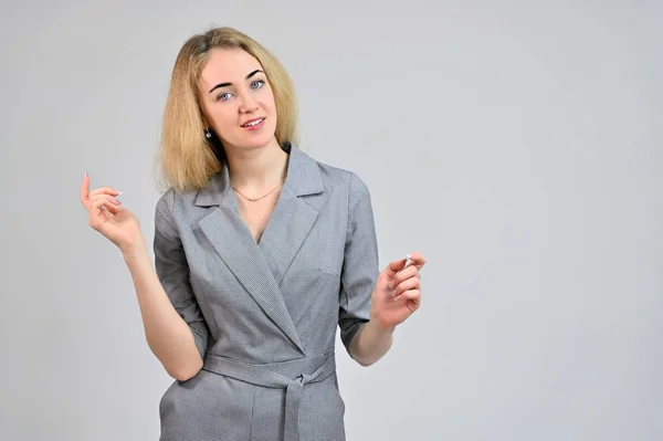 Model Standing directly in front of the camera in various poses. Portrait of a pretty cute smiling young blonde business woman with minimal makeup in a gray suit on a white background. — Stock Photo, Image