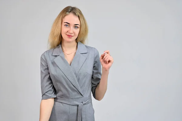 Model Direct voor de camera staan in verschillende standen. Portret van een leuke glimlachende jonge blonde zakenvrouw met minimale make-up in een grijs pak op een witte achtergrond. — Stockfoto