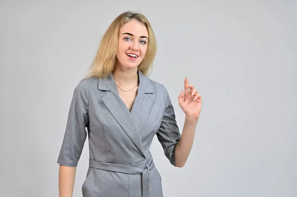 Model Standing directly in front of the camera in various poses. Portrait of a pretty cute smiling young blonde business woman with minimal makeup in a gray suit on a white background. — 스톡 사진