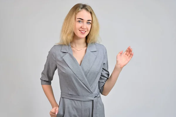 Portrait of a pretty cute smiling young blonde business woman with minimal makeup in a gray suit on a white background. Model Standing directly in front of the camera in various poses. — Stock Photo, Image