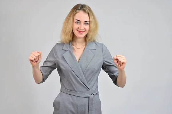 Portrait of a pretty cute smiling young blonde business woman with minimal makeup in a gray suit on a white background. Model Standing directly in front of the camera in various poses. — 스톡 사진