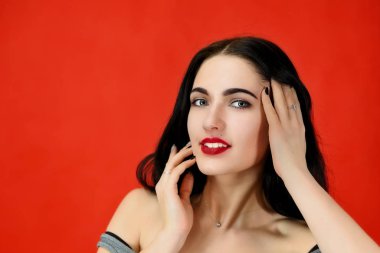 Mükemmel makyaj ve kozmetik konsepti. Güzel esmer bir kızın yakın plan portresi mükemmel makyajlı ve lüks saçlı stüdyodaki kırmızı arka planda..