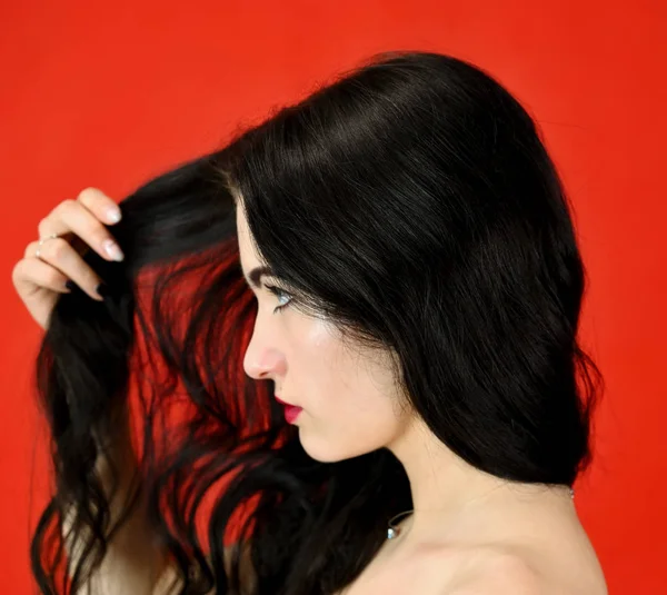 Il concetto di capelli lunghi e belli. Primo piano Ritratto di una bella ragazza modello bruna con ottimo trucco e capelli lussuosi su uno sfondo rosso in studio . — Foto Stock