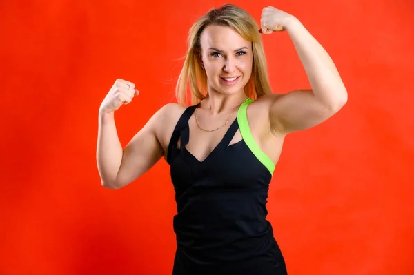 Le concept de fitness à la mode. Photo d'une belle jolie femme mince sportive blonde en survêtement sur fond rouge. Debout dans différentes poses avec des émotions et un sourire . — Photo