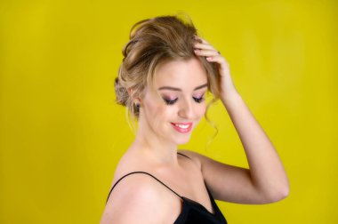 Güzel sarışın bir mankenin göz kamaştırıcı bir portresi mükemmel makyajlı ve sarı arka planda güzel bir saç stili. Kozmetik, moda ve tarz kavramı.