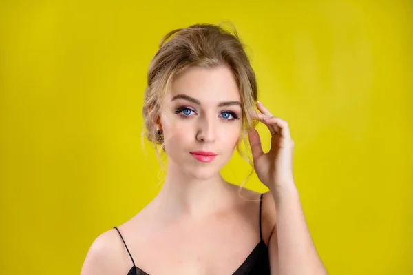 The concept of cosmetics, fashion and style. Glamorous beauty portrait of a pretty blonde model with excellent makeup and a beautiful hairstyle on a yellow background in the studio. — ストック写真
