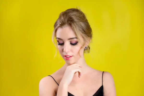 Le concept de cosmétiques, de mode et de style. Portrait de beauté glamour d'une jolie mannequin blonde avec un excellent maquillage et une belle coiffure sur fond jaune en studio . — Photo