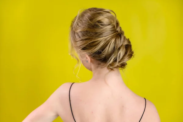 Glamorous beauty rear view portrait of a pretty blonde model with excellent make-up and beautiful hairstyle on a yellow background in the studio. The concept of cosmetics, fashion and style. — 图库照片