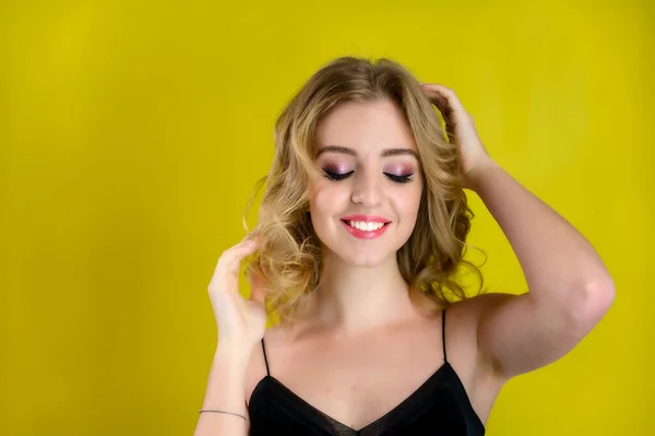 Glamorous beauty front view portrait of a pretty model with blond hair with great makeup and a beautiful hairstyle on a yellow background in the studio. The concept of cosmetics, fashion and style. — Stok fotoğraf