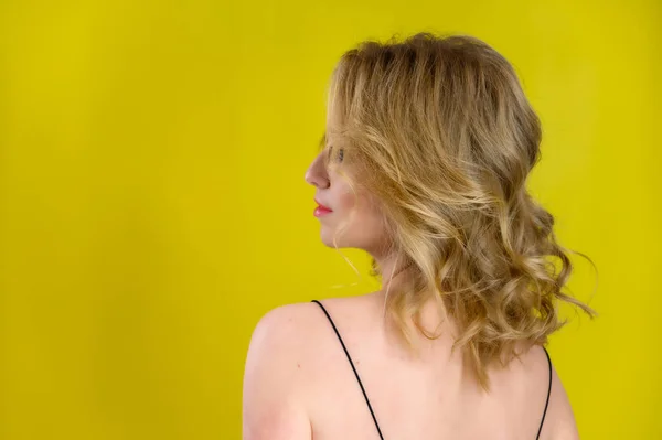 Glamorous beauty rear view portrait of a pretty model with blond hair with great makeup and a beautiful hairstyle on a yellow background in the studio. The concept of cosmetics, fashion and style. — 스톡 사진