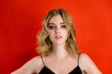 Kozmetik, moda ve tarz kavramı. Göz kamaştırıcı güzel bir ön manzara portresi. Sarı saçlı, harika makyajlı ve güzel bir saç stili olan güzel bir model. Stüdyonun kırmızı arka planında..