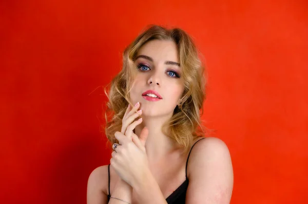 Glamorös skönhet front visa porträtt av en vacker modell med blont hår med stor makeup och en vacker frisyr på en röd bakgrund i studion. Begreppet kosmetika, mode och stil. — Stockfoto