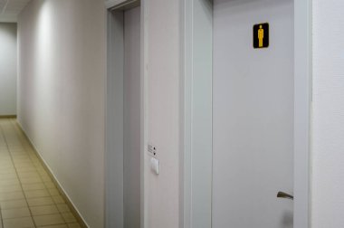 Binanın koridoru, tuvaletin kapısı ve beyaz duvarları var..