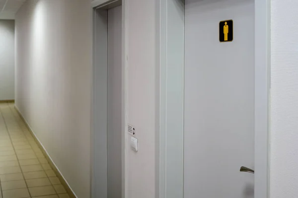 Korytarz w budynku z drzwiami do toalety i białymi ścianami. — Zdjęcie stockowe