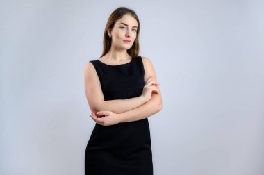 Bir kadın kameraya konuşuyor. Beyaz arka planda siyah elbiseli güzel bir kızın fotoğrafı..