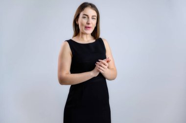 Bir kadın kameraya konuşuyor. Beyaz arka planda siyah elbiseli güzel bir kızın fotoğrafı..