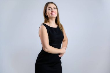Beyaz arka planda iş portresi. Siyah elbiseli, gülümseyen, sempatik beyaz kadın.