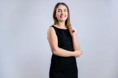 Beyaz arka planda iş portresi. Siyah elbiseli, gülümseyen, sempatik beyaz kadın.