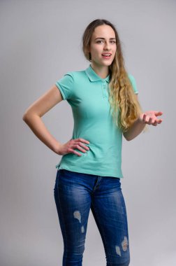 Evrensel bir kavram. Model gülümseyerek konuşuyor. Beyaz arka planda uzun saçlı, turkuaz tişörtlü ve kot pantolonlu beyaz bir kadının dikey portresi..