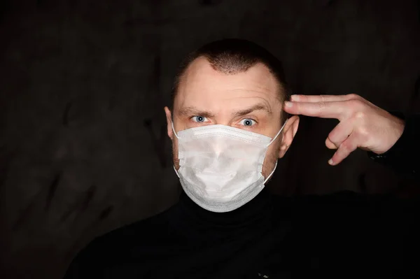 A large photo of a man in a medical mask scared on a black background