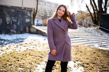 Güneşli bir günde binanın arka planında pembe ceketli, güzel, güzel, beyaz saçlı bir kızın portresi..