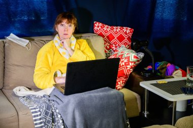 Karantinada, kanepesinde koronavirüs olan bir kadının fotoğrafı. Model dizüstü bilgisayar kullanıyor.