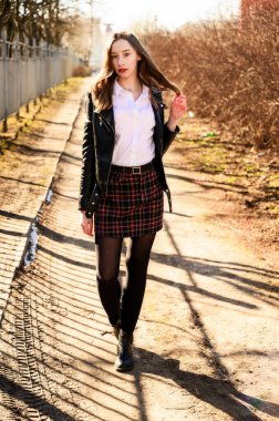 Açık havada duyguları olan gülümseyen güzel bir kızın tam boy bahar portresi. Model kameranın önünde beyaz bir bluz ve ceket giyiyor.