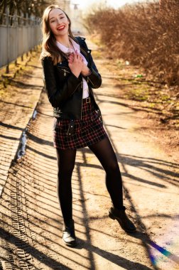 Açık havada duyguları olan gülümseyen güzel bir kızın tam boy bahar portresi. Model kameranın önünde beyaz bir bluz ve ceket giyiyor.