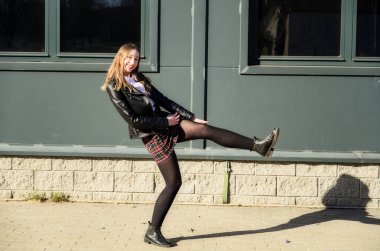 Kameranın önünde şaka gibi poz ver. Şehrin arka planında, güneşte duyguları olan mutlu ve güzel bir kızın bahar fotoğrafı..