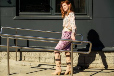 Güneşli bahar aylarında binanın arka planında uzun saçlı, şık ve alımlı güzel bir kadının parlak havasında çekilmiş bir fotoğraf..