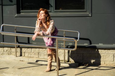 Güneşli bahar aylarında binanın arka planında uzun saçlı, şık ve alımlı güzel bir kadının parlak havasında çekilmiş bir fotoğraf..