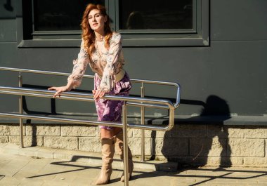 Güneşli bahar aylarında binanın arka planında uzun saçlı, şık ve alımlı güzel bir kadının parlak havasında çekilmiş bir fotoğraf..