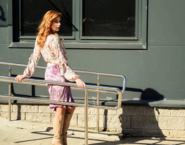 Güneşli bahar aylarında binanın arka planında uzun saçlı, şık ve alımlı güzel bir kadının parlak havasında çekilmiş bir fotoğraf..